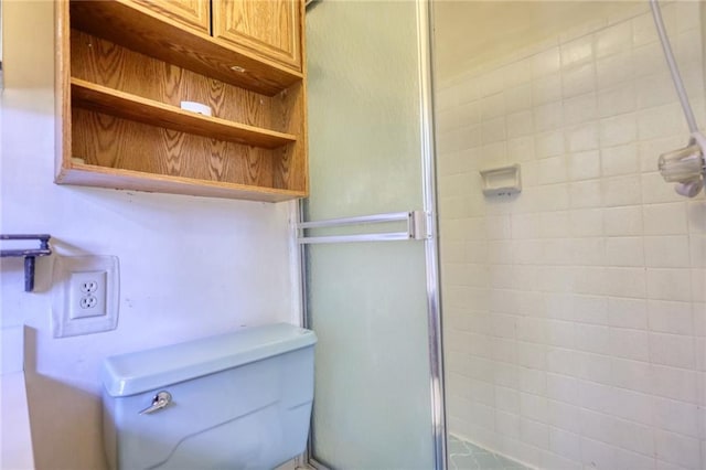 bathroom featuring a shower with door and toilet