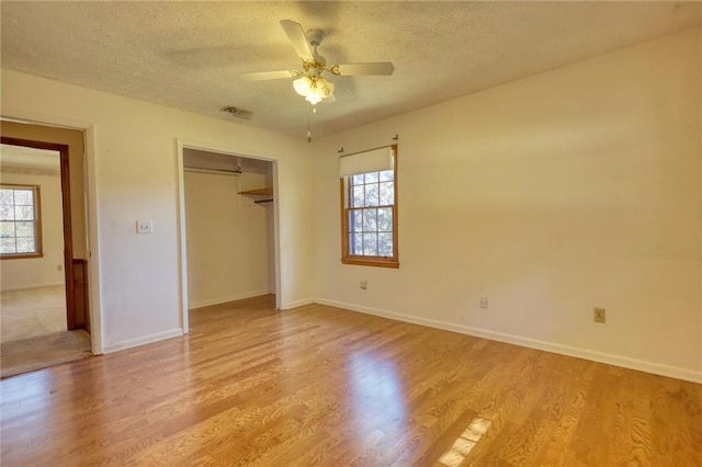 unfurnished bedroom with a textured ceiling, a closet, light hardwood / wood-style floors, and ceiling fan