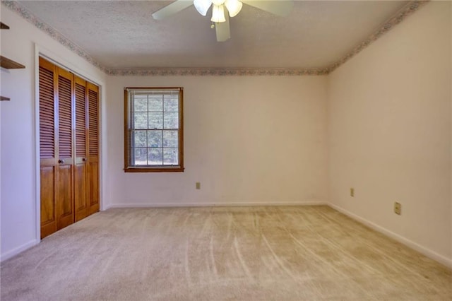 unfurnished bedroom featuring light carpet, a textured ceiling, a closet, and ceiling fan