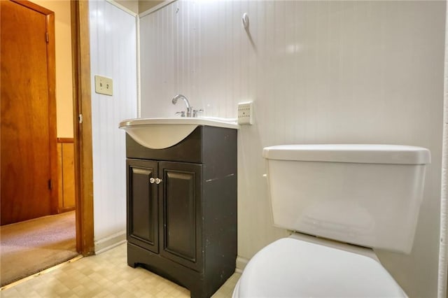 bathroom with vanity, toilet, and wood walls