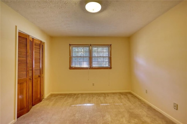 unfurnished bedroom with a closet, light colored carpet, and a textured ceiling