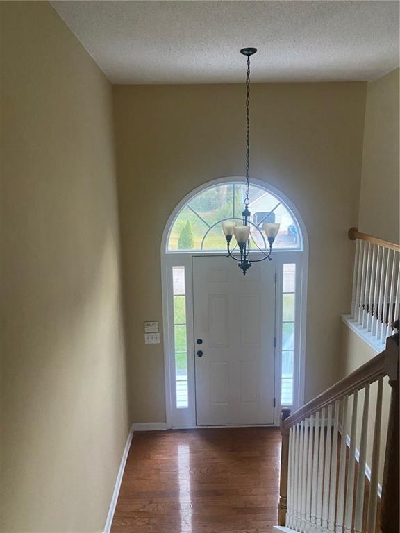 entrance foyer with a notable chandelier, a textured ceiling, and dark hardwood / wood-style flooring