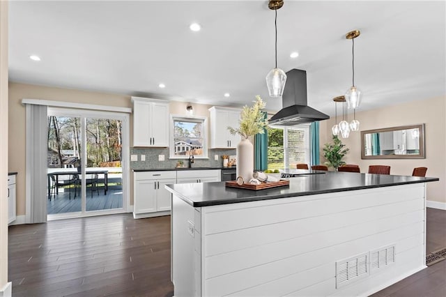 kitchen featuring dark countertops, tasteful backsplash, a sink, island exhaust hood, and dark wood-style flooring