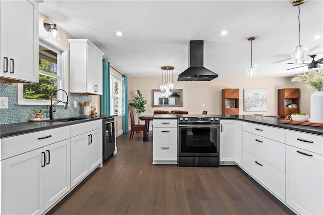 kitchen featuring dark countertops, electric range, wall chimney range hood, and a sink