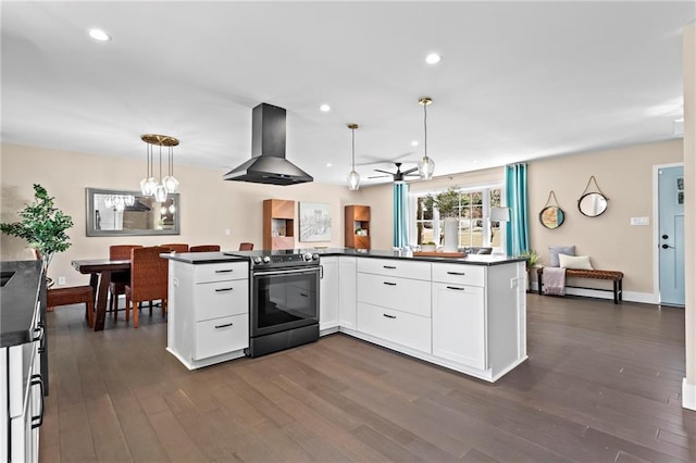 kitchen featuring dark countertops, wall chimney range hood, dark wood finished floors, stainless steel electric stove, and white cabinets