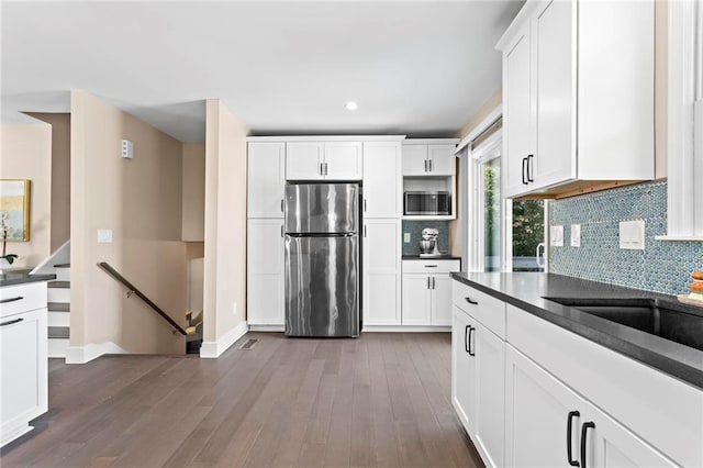 kitchen with decorative backsplash, dark countertops, dark wood-style floors, and appliances with stainless steel finishes