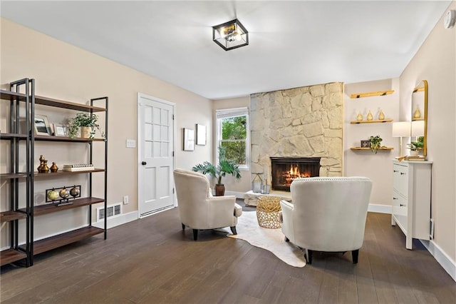 living room featuring dark wood-style floors, visible vents, a fireplace, and baseboards