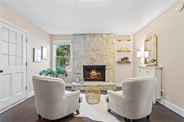 living area with a fireplace, dark wood-type flooring, and baseboards