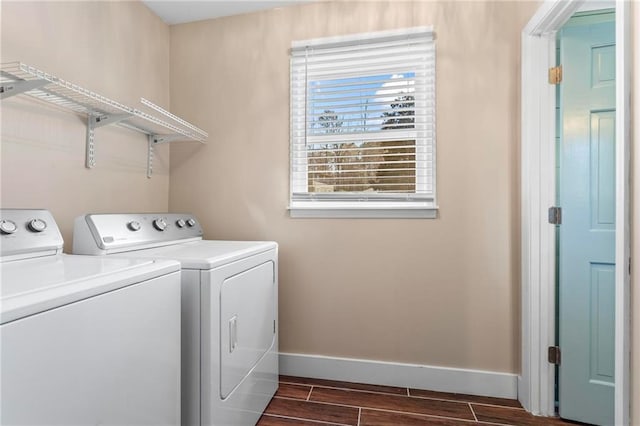 clothes washing area with laundry area, wood tiled floor, baseboards, and washing machine and clothes dryer