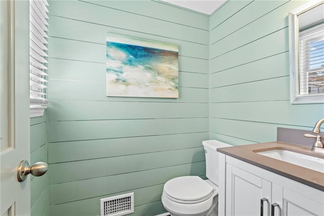 half bath with visible vents, toilet, and vanity