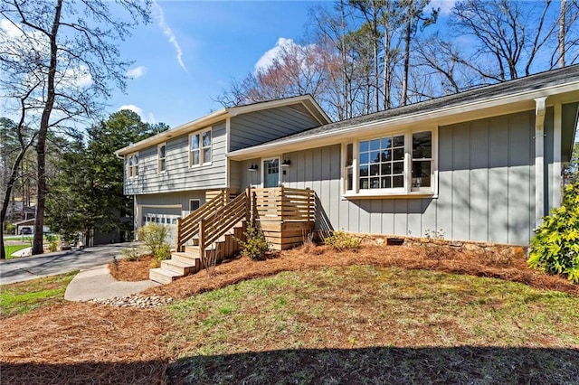 split level home with a garage, board and batten siding, and driveway