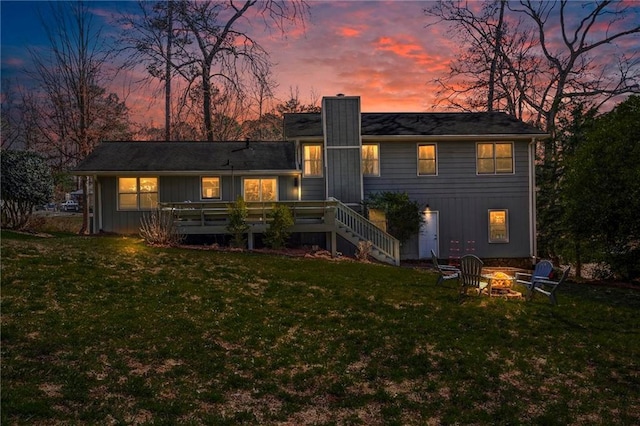 rear view of property featuring a yard and an outdoor fire pit