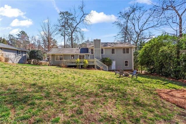 back of property with a yard, a wooden deck, and an outdoor fire pit