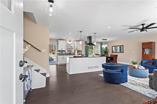 living room featuring dark wood-style floors, visible vents, a ceiling fan, recessed lighting, and stairs