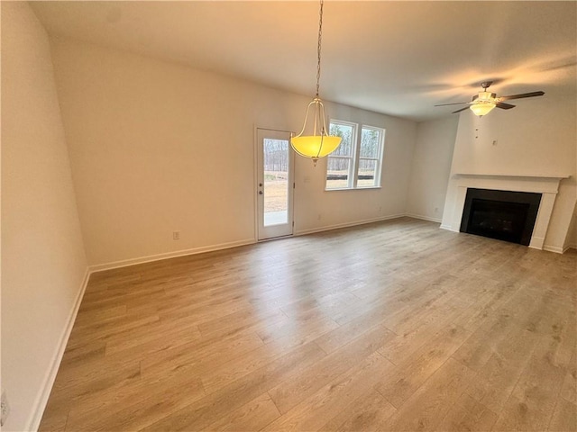 unfurnished living room featuring a ceiling fan, light wood-type flooring, a fireplace, and baseboards