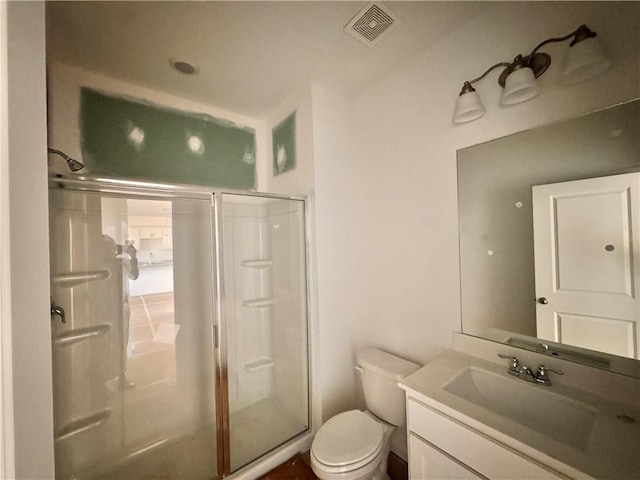 bathroom featuring vanity, toilet, and a shower with shower door