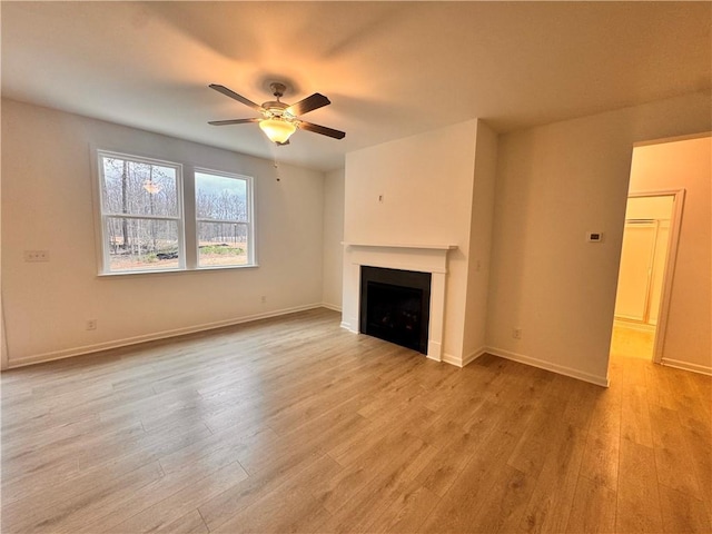 unfurnished living room featuring a ceiling fan, light wood-type flooring, a fireplace, and baseboards