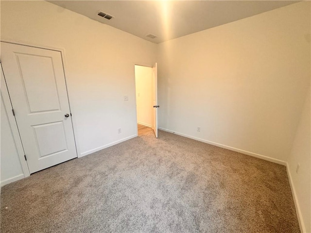 spare room featuring baseboards, visible vents, and carpet flooring