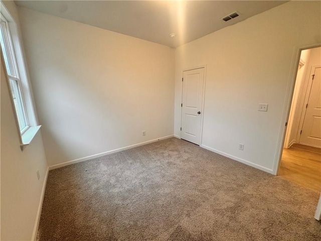 carpeted empty room with plenty of natural light, visible vents, and baseboards