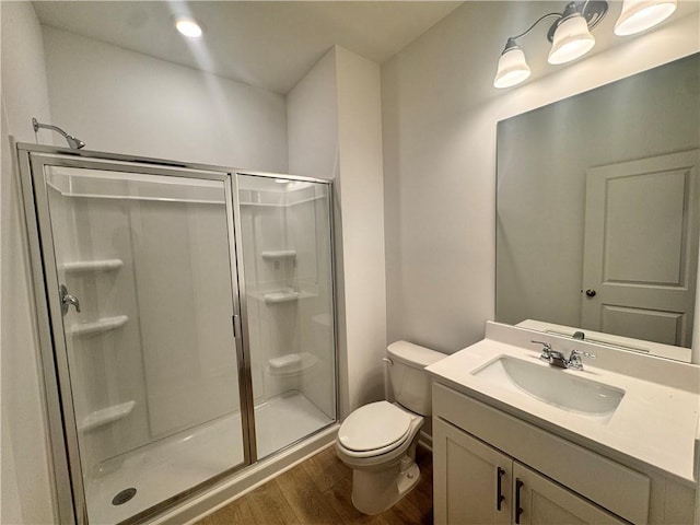 bathroom with vanity, a shower stall, toilet, and wood finished floors