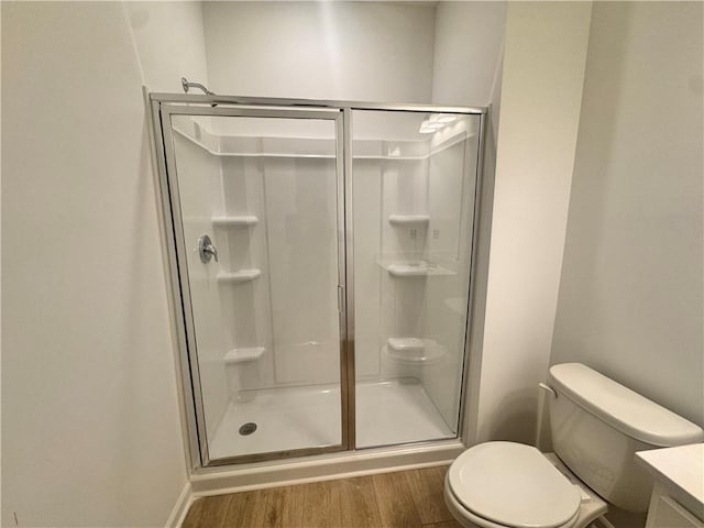 bathroom with vanity, wood finished floors, toilet, and a shower stall