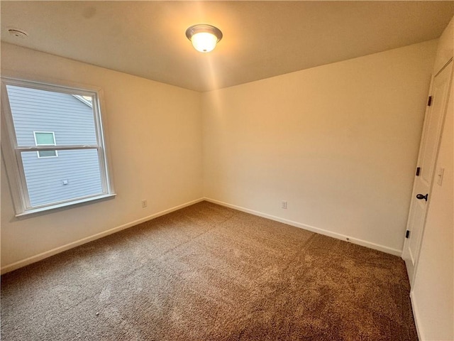 spare room featuring carpet and baseboards