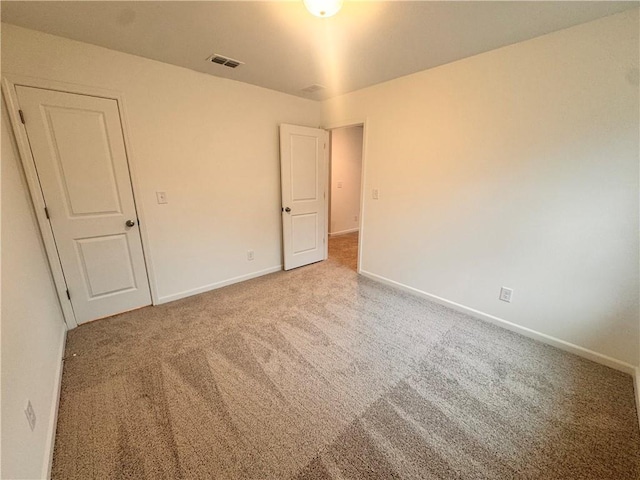 carpeted spare room with visible vents and baseboards