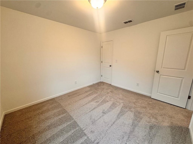 unfurnished room with carpet floors, visible vents, and baseboards