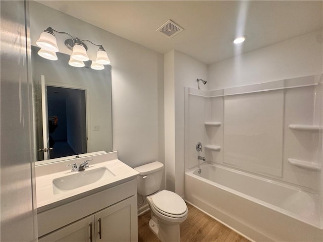 full bath with visible vents, bathing tub / shower combination, toilet, wood finished floors, and vanity