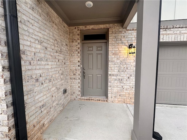 property entrance featuring a garage and brick siding