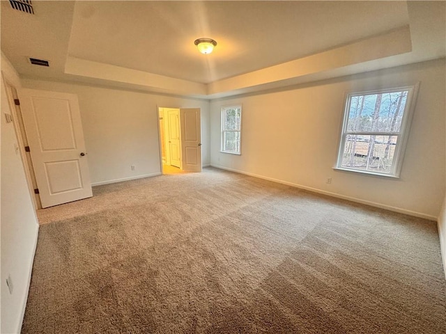 unfurnished bedroom featuring carpet floors, a raised ceiling, visible vents, and baseboards