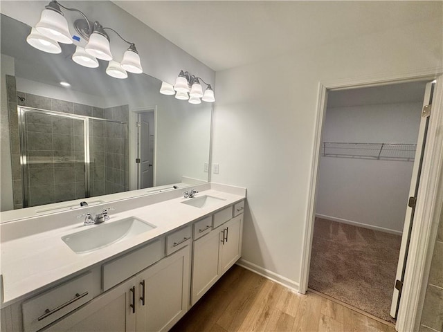 bathroom featuring a walk in closet, a sink, a shower stall, and double vanity