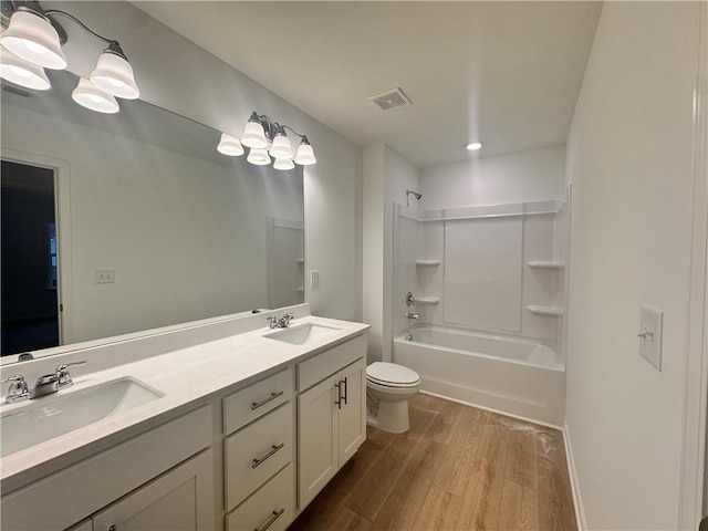 bathroom with tub / shower combination, a sink, toilet, and wood finished floors