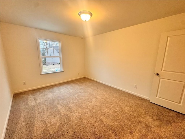 spare room featuring carpet and baseboards