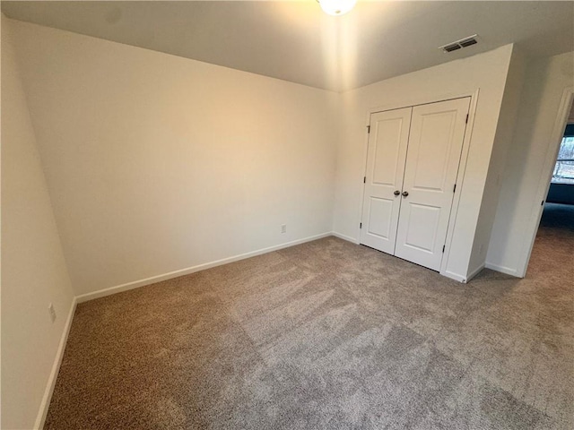 unfurnished bedroom with carpet floors, a closet, visible vents, and baseboards