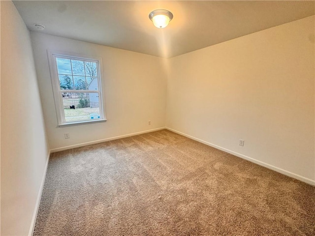 carpeted spare room featuring baseboards