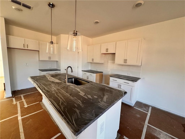 kitchen with hanging light fixtures, sink, white cabinets, and a kitchen island with sink