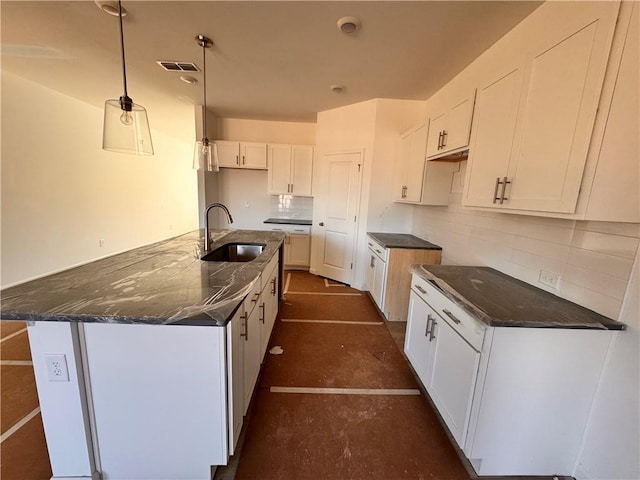 kitchen featuring a sink, visible vents, white cabinetry, backsplash, and dark stone countertops