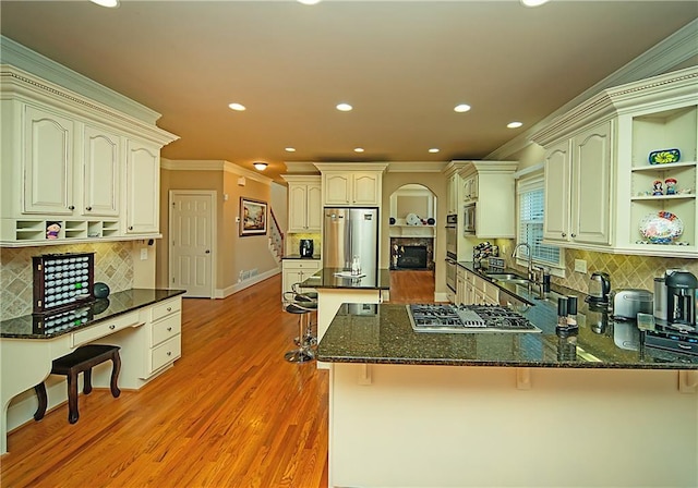 kitchen featuring a fireplace, open shelves, appliances with stainless steel finishes, a peninsula, and a kitchen breakfast bar