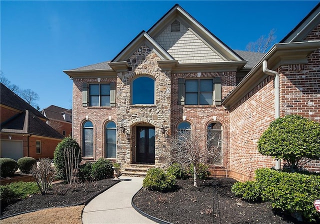 view of front of house featuring stone siding, french doors, and brick siding