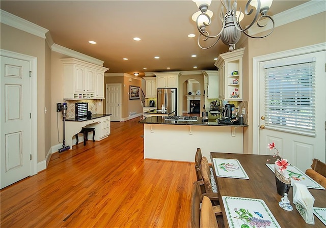 kitchen with dark countertops, appliances with stainless steel finishes, ornamental molding, a peninsula, and open shelves