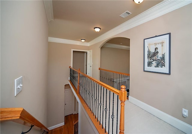 hall with visible vents, ornamental molding, an upstairs landing, and baseboards