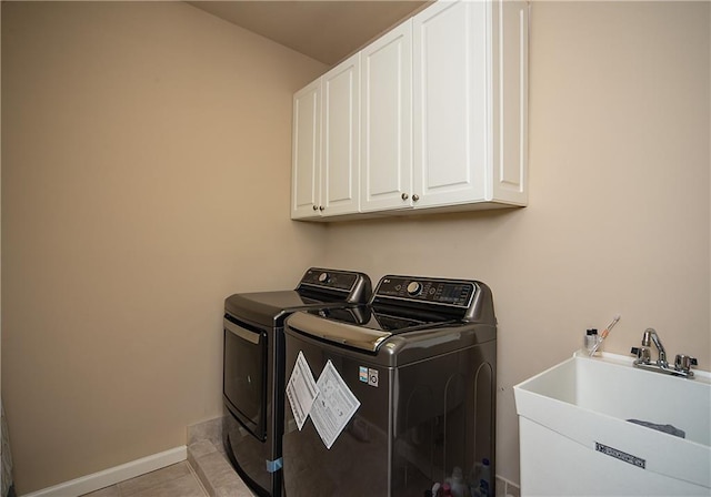 laundry area featuring light tile patterned flooring, washing machine and dryer, a sink, baseboards, and cabinet space