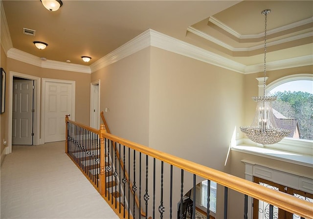 hallway featuring a chandelier, carpet flooring, an upstairs landing, visible vents, and crown molding