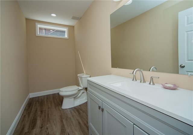 bathroom with recessed lighting, toilet, vanity, wood finished floors, and baseboards