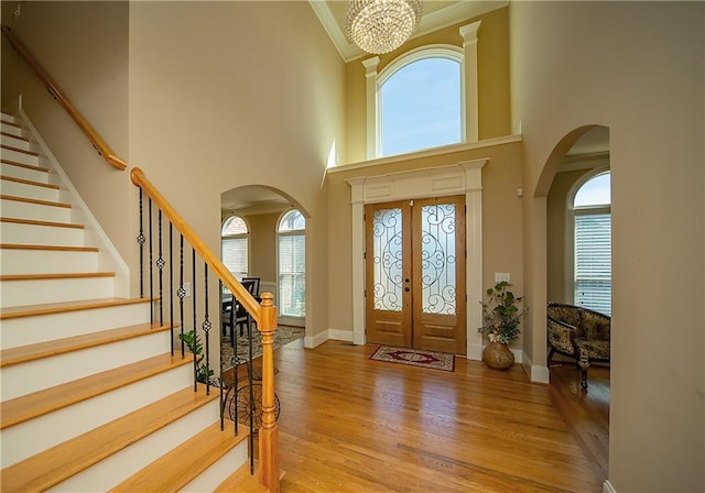 entrance foyer with stairs, ornamental molding, arched walkways, and wood finished floors