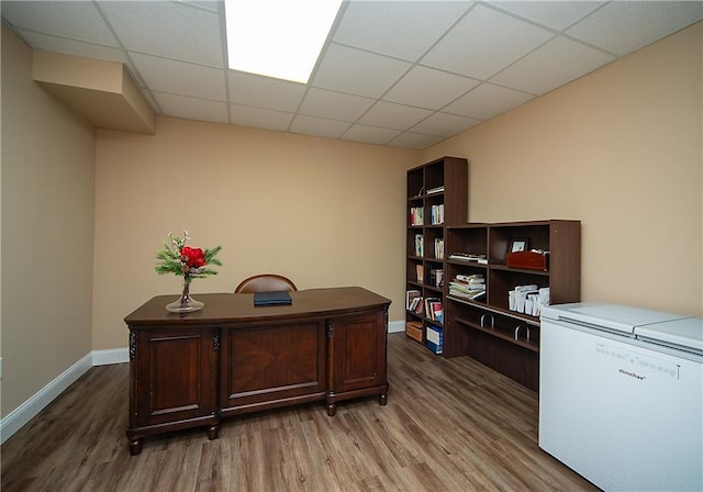 office area with a paneled ceiling, baseboards, and wood finished floors