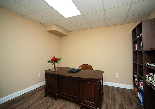 office featuring a paneled ceiling, baseboards, and dark wood-type flooring