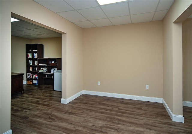 unfurnished room featuring a paneled ceiling, baseboards, and dark wood-type flooring