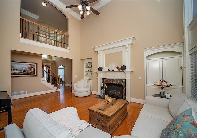 living area featuring baseboards, visible vents, wood finished floors, stairs, and a fireplace